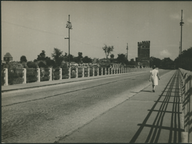 Na zdjęciu widać kobietę spacerującą mostem drogowym na Nogacie. W tle zdjęcia widoczna jest Baszta Sztumska.